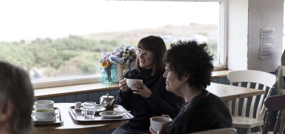 Visitors enjoying a hot drink in the Coastguard Lookout, above the Coastguard Cottages Tearoom
