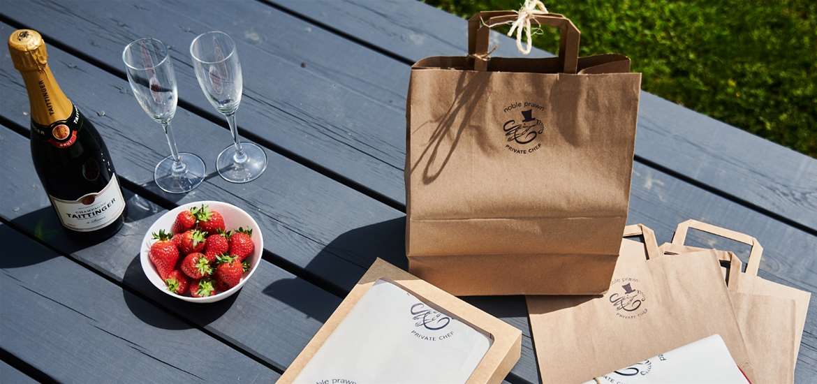 Noble Prawn - Paper bag with champagne, glasses and strawberries