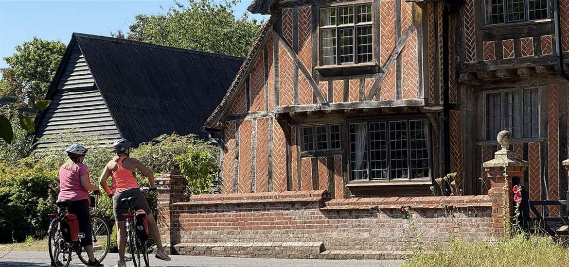 Touring cyclists admire half timbered house in Suffolk