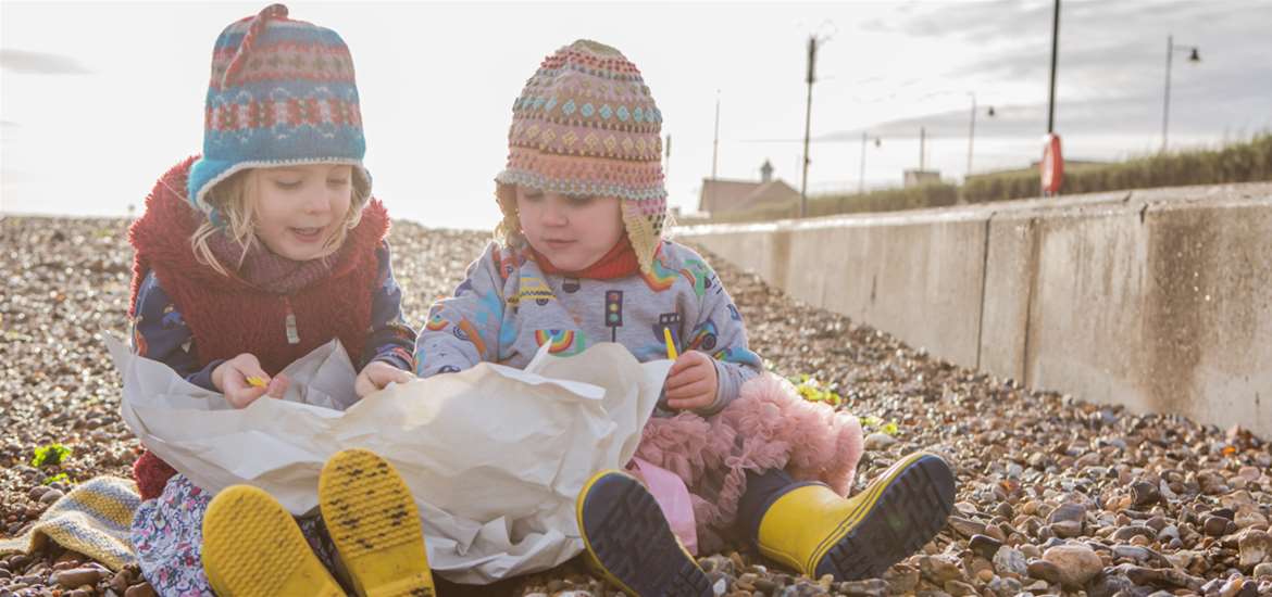 Children sit on a beach eating fish and chips at Felixstowe